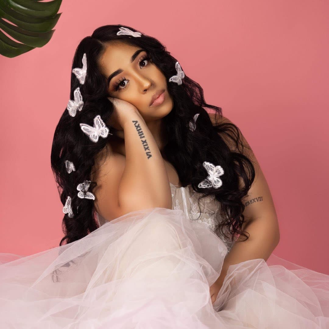 Bella Veronica in white tulle with butterflies in her hair on a pink ground.