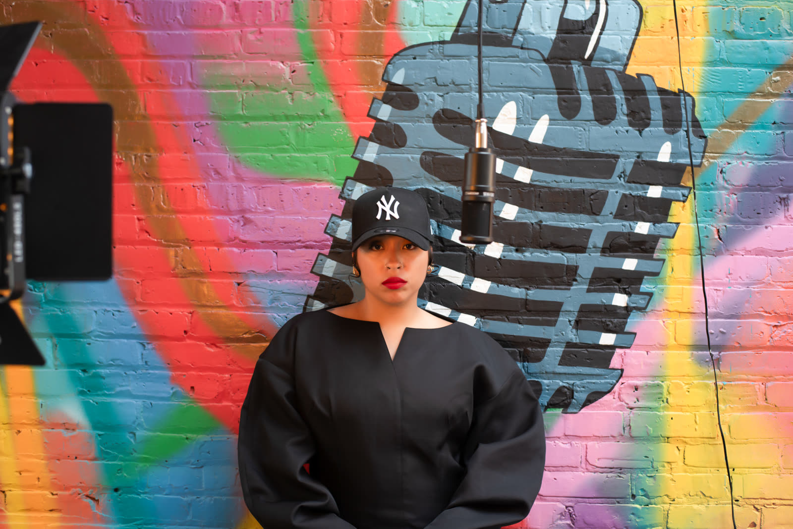 Bella Veronica standing in front of a painted mural of a vintage microphone.